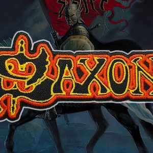 May include: Embroidered patch with the word "SAXON" in orange and yellow lettering with a black outline. The patch has a white border and is set against a background of a knight on horseback.