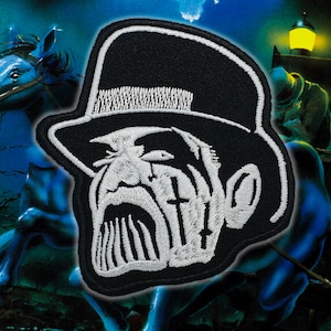 May include: Black and white embroidered patch featuring a stylized face with a top hat. The face has a grim expression with cross-shaped markings. The patch is set against a dark, fantasy-themed background with a horse-drawn carriage.