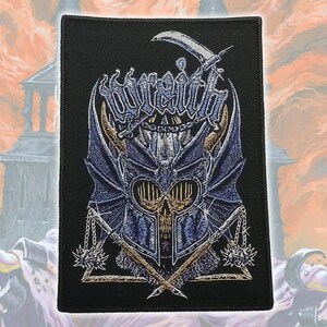 May include: A rectangular black embroidered patch featuring a central blue and silver armored helmet with horns, a skull face, and wings. Above the helmet, the word "wraith" is stitched in a stylized font with a scythe, and two spiked maces cross below.