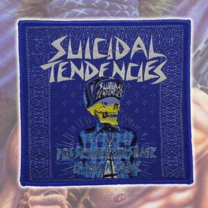 May include: A square embroidered patch featuring a blue background with a yellow skull wearing a blue cap and a blue plaid shirt. The text reads Suicidal Tendencies at the top and Possessed to Skate Is Not a Crime at the bottom in white lettering.