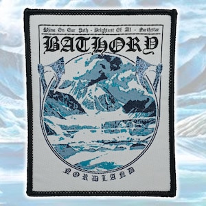 May include: A rectangular embroidered patch with a black border featuring a white background. It displays the text BATHORY at the top and NORDLAND at the bottom. The center shows a blue and white mountain landscape with two axes on the sides.