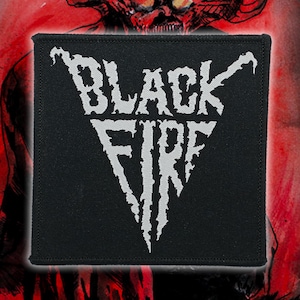May include: Black square patch with the words "BLACK FIRE" in white, stylized, jagged lettering. The patch has a black border and is set against a blurred red background with a demonic figure.