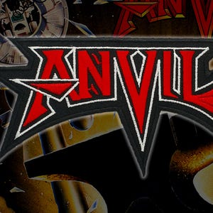 Puede incluir: Parche bordado con la palabra "ANVIL" en rojo, con borde blanco, sobre fondo negro. El parche tiene forma de estrella y está diseñado para coserlo a la ropa. El fondo tiene un tema metálico borroso.