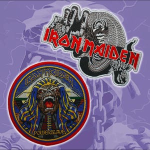 Puede incluir: Dos parches bordados con imágenes de Iron Maiden. El parche superior muestra el nombre de la banda en letras rojas sobre un gráfico en blanco y negro. El parche circular inferior representa un personaje faraón con el texto Iron Maiden y Powerslave.