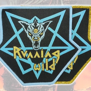 Op de afbeelding: Twee geborduurde patches met een zwarte pentagramvorm en lichtblauwe randen. Het midden toont een gestileerde dierenkop met een gouden ring in de neus, boven de goud geborduurde tekst "RUNNING WILD" in een uniek lettertype.