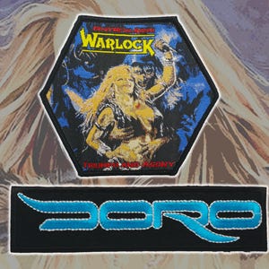 Op de afbeelding: Een zeshoekige geborduurde patch met de Warlock Triumph and Agony albumhoes met een blonde figuur en blauwe tinten, gecombineerd met een rechthoekige zwarte patch met het woord Doro in felblauw gestileerde geborduurde letters.