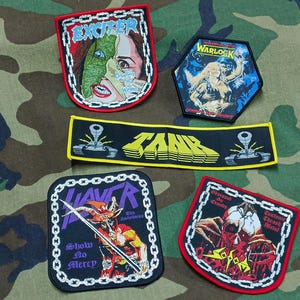 May include: Five embroidered fabric patches featuring heavy metal band logos and artwork. The collection includes Exciter, Warlock, Tank, Slayer, and Sodom designs, each with distinct graphic illustrations, chain-link borders, and bold lettering.