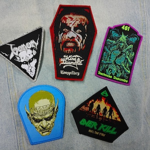 以下が含まれることがあります： バンドのロゴやアートワークが刺繍された5つのワッペン。三角形のVenomワッペン、棺桶型のKing Diamondワッペン、長方形のDarkness Descendsワッペン、青いKreatorワッペン、三角形のOverkill Feel the Fireワッペンが含まれています。