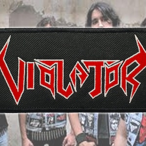 Op de afbeelding: Zwart rechthoekig embleem met het woord "VIOLATOR" in rood, omlijnd met wit. De tekst heeft een scherpe, hoekige lettertype. Het embleem is waarschijnlijk voor een band of muziekgerelateerd item.