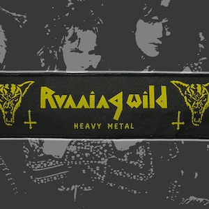 May include: Black rectangular patch with yellow text and graphics. The text reads "Running Wild" above "Heavy Metal." The patch features a horned skull graphic on each side and crosses. The background is a gray and black image of people.