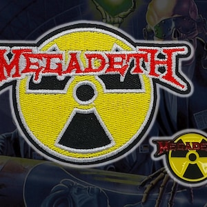 May include: Embroidered patch and pin featuring the band name "Megadeth" in red, outlined in white, above a yellow radiation symbol with a black centre. The patch and pin are set against a dark background with a figure in the background.
