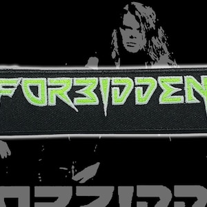 May include: A black rectangular patch with the word "FORBIDDEN" embroidered in neon green. The patch has a white border and is set against a black background with blurred grayscale images of people.