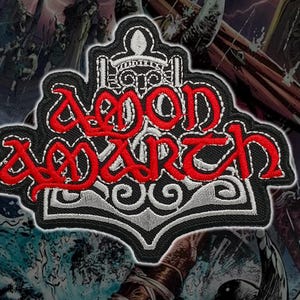 Puede incluir: Parche bordado con el texto "AEON ARCH" en rojo, con letras estilizadas. El parche tiene un borde negro y un diseño decorativo blanco y gris. El fondo presenta una ilustración de fantasía.