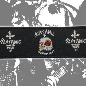 Puede incluir: Un parche rectangular negro bordado que presenta el texto SLATANIC WORLD TOUR '85 en los lados izquierdo y derecho con una cruz invertida. El centro muestra un gráfico de calavera con el texto SLATANIC WEHRMACHT y un emblema de Slayer.