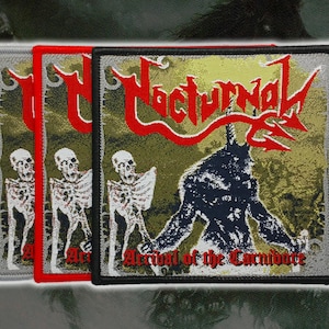 May include: Three square patches with embroidered designs. The patches feature the word "Nocturnal" in red, a skeletal figure, and a horned demon. The text "Arrival of the Carnivore" is also present. The patches have gray, red, and black borders.