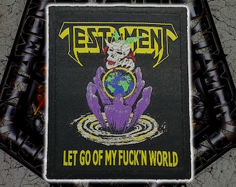 May include: A rectangular black embroidered patch featuring the yellow text TESTAMENT at the top. Below is a white skull with green accents above a globe held by purple hands emerging from water. The yellow text LET GO OF MY FUCK'N WORLD is at the bottom.