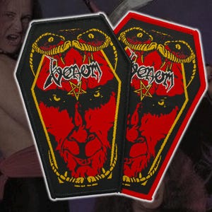 May include: Two coffin-shaped patches featuring a red demonic face with a pentagram and the word "Venom" in white. The patches have a black border with yellow accents and a snake design at the top. The background is dark.