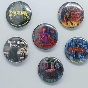 Puede incluir: Cinco chapas redondas con ilustraciones gráficas coloridas y logotipos de bandas. Los diseños incluyen Benediction, Demolition Hammer, Gorguts y otras imágenes de música metal con textos como Transcend the Rubicon y Epidemic of Violence.