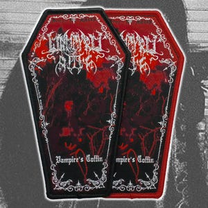 May include: Two coffin-shaped embroidered patches featuring a black and red color scheme. The design includes intricate white filigree borders, stylized white text at the top, and the words Vampire's Coffin printed in white at the bottom.