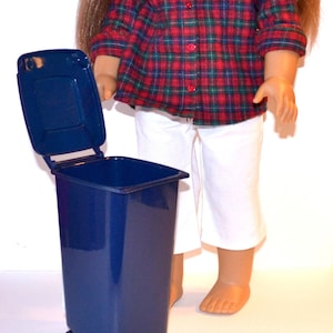 May include: A blue plastic trash can with a lid that is open. The trash can has a small wheel on the bottom.
