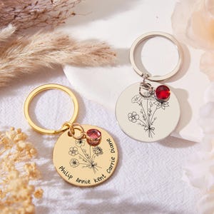 Può includere: Due portachiavi in oro e argento con un design floreale e un piccolo strass rosso. Il portachiavi in oro ha i nomi "Philip, Annie, Kent, Carrie, Diane" incisi su di esso.