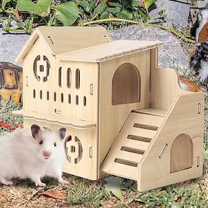 Può includere: Una casetta di legno per criceti con una rampa, una piattaforma e una piccola porta. La casetta è dipinta di un colore legno chiaro e ha una piccola finestra. Un criceto bianco è seduto davanti alla casetta.