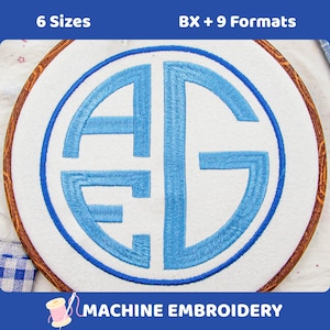 May include: A circular embroidery hoop containing white fabric with a light blue stitched monogram featuring the letters A, E, and G inside a circular border. The text 6 Sizes and BX + 9 Formats appears at the top, with MACHINE EMBROIDERY at the bottom.