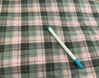 May include: A pink, gray, and white plaid fabric with a white pen with a blue tip. The fabric has a classic checkered pattern, with the pen resting diagonally across the fabric.