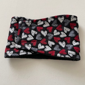 May include: Black headband with a pattern of red, white, and gray hearts. The hearts are drawn with a sketchy, chalk-like texture. The headband is folded over, showing the interior black fabric.