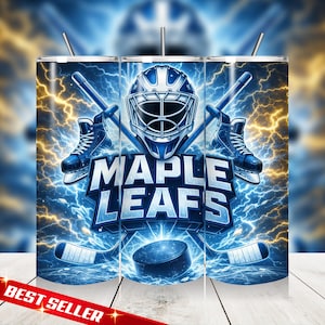 Puede incluir: Un vaso con un diseño de hockey. El diseño presenta una máscara de portero de hockey azul, patines y palos de hockey cruzados sobre un fondo de relámpagos y las palabras "MAPLE LEAFS". El vaso tiene una pajita y las palabras "BEST SELLER" en la parte inferior.