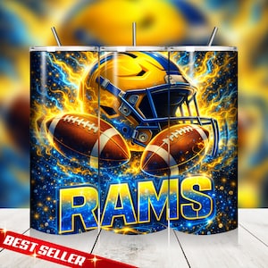 May include: A tumbler featuring a football helmet and two footballs in a vibrant design with blue and yellow accents. The word "RAMS" is prominently displayed in a bold, stylized font. The background has a dynamic, electric energy.