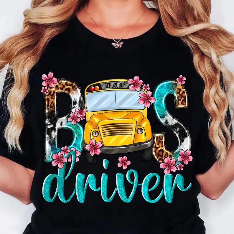May include: Black t-shirt with a graphic design featuring the words "Bus driver" in turquoise script. The word "Bus" is stylized with animal print and floral accents, and a yellow school bus is in the center.