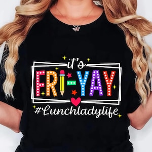K&ouml;nnte beinhalten: Schwarzes T-Shirt mit dem Text "it's FRI-YAY" in bunten Buchstaben, einer Bleistiftgrafik und dem Hashtag "#Lunchladylife". Das Design beinhaltet einen wei&szlig;en rechteckigen Rahmen, Sterne und ein Herz.