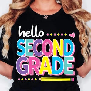 May include: A black t-shirt featuring the white text hello followed by colorful dots and a small pink heart. Below, the words SECOND GRADE are printed in large, bold, multi-colored letters. A yellow pencil graphic sits at the bottom of the design.