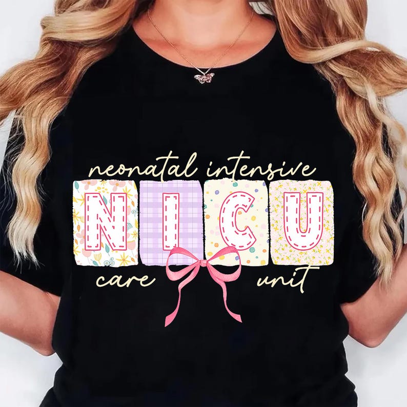 May include: Black t-shirt with the words "neonatal intensive NICU care unit" in a whimsical font. The letters NICU are in colorful, patterned blocks with a pink bow. A necklace with a butterfly pendant is visible.
