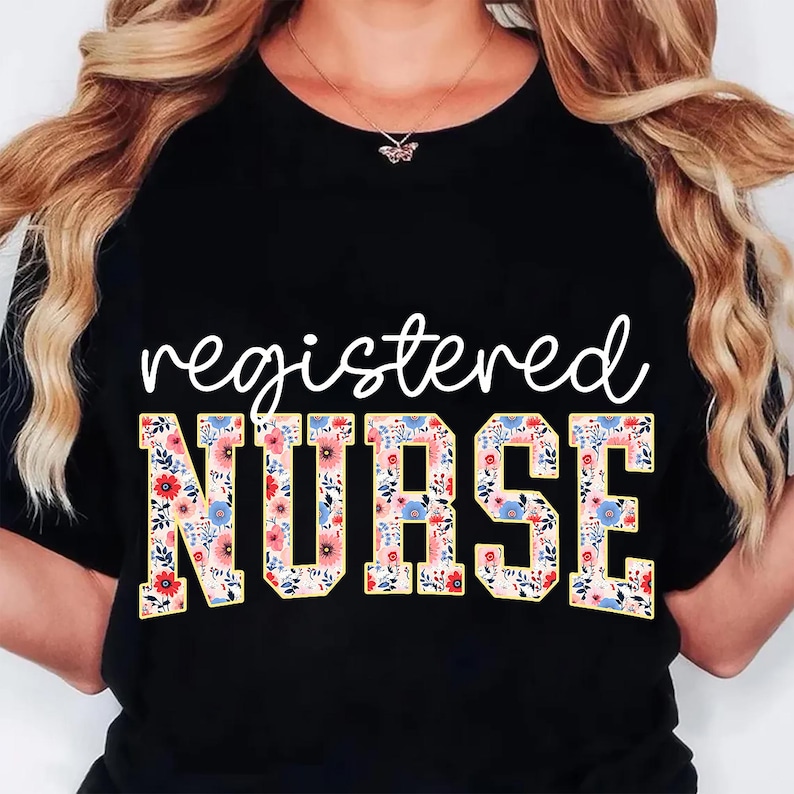 Pu&ograve; includere: T-shirt nero con le parole "registered NURSE" in corsivo bianco e lettere a blocchi floreali. Il design floreale comprende fiori rosa, blu e gialli su sfondo crema. La maglietta &egrave; a girocollo.