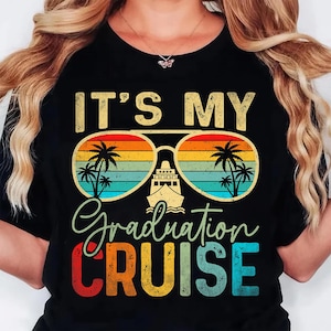 May include: Black t-shirt with the text "IT'S MY Graduation CRUISE" in a retro font. The design features sunglasses with a sunset gradient, palm trees, and a cruise ship, perfect for a graduation celebration.