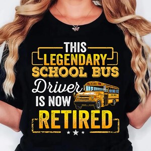 May include: Black t-shirt with a yellow graphic that reads "THIS LEGENDARY SCHOOL BUS Driver IS NOW RETIRED." The graphic includes a yellow school bus illustration and three stars.