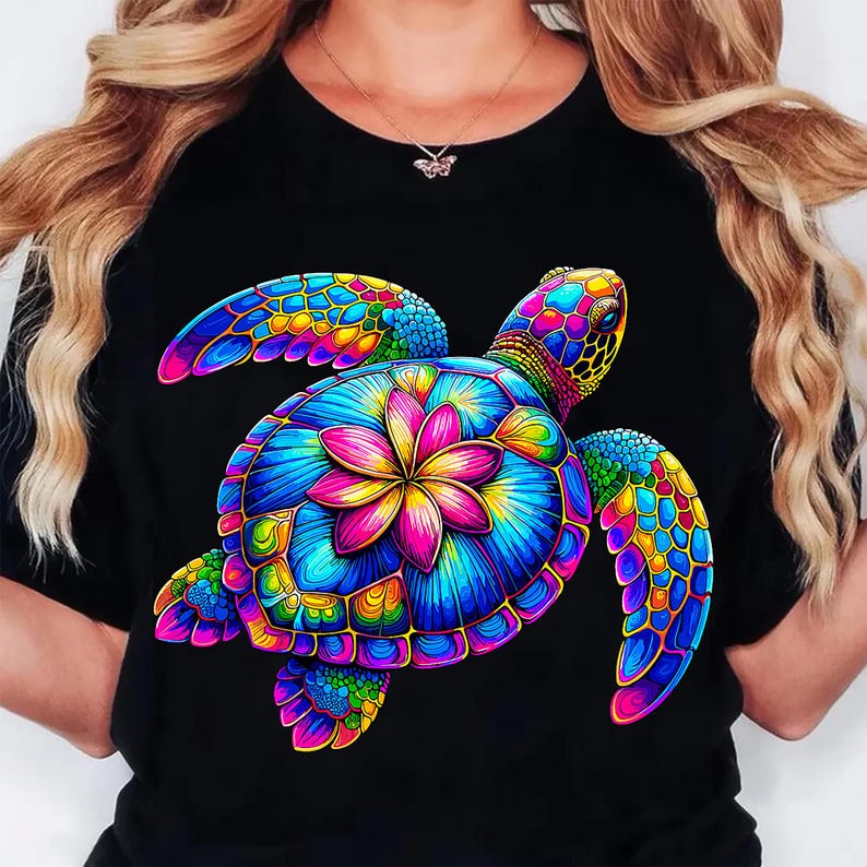 May include: Black t-shirt featuring a vibrant, colorful sea turtle design. The turtle's shell is a mosaic of blues, greens, yellows, and pinks, with a central flower motif. The design is detailed and eye-catching, perfect for a casual look.