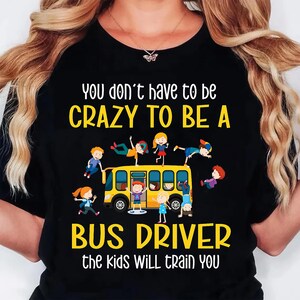 May include: Black t-shirt with a yellow school bus graphic and the text "You don't have to be CRAZY TO BE A BUS DRIVER the kids WILL train You." The graphic includes cartoon children.