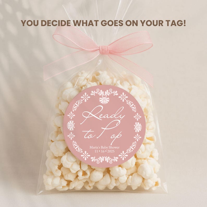 May include: A clear cellophane bag filled with popcorn, tied with a pink ribbon. A round, pink tag with white floral accents reads "Ready to Pop" with event details. The text "YOU DECIDE WHAT GOES ON YOUR TAG!" is at the top.