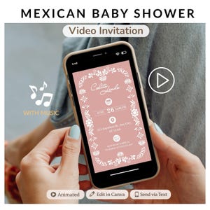 May include: A smartphone displays a pink baby shower video invitation with white floral accents and the text "Mexican Baby Shower." The phone also shows the text "Celita Linda," date, time, and address. The phone is held in a person's hands.
