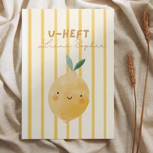 May include: A rectangular art print featuring a yellow lemon illustration with a smiling face and green leaves. The background has vertical yellow stripes. The text "U-HEFT Liana Sophie" is printed at the top. The print is on a beige fabric.