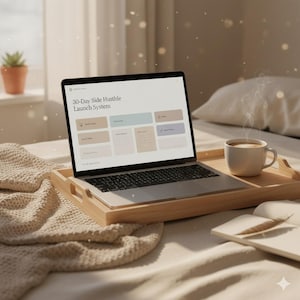 Könnte beinhalten: Ein Laptop mit der Anzeige "30-Day Side Hustle Launch System" auf einem Holztablett mit einer Kaffeetasse. Das Tablett steht auf einem Bett mit einer cremefarbenen Decke und einem Kissen. Eine kleine Topfpflanze ist im Hintergrund zu sehen.