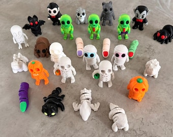 Peut inclure: Une collection de petites figurines sur le thème d'Halloween. Les figurines comprennent des extraterrestres, des momies, des squelettes, des vampires, des araignées et des personnages à tête de citrouille. Les figurines sont de différentes couleurs, dont le vert, l'orange, le noir, le blanc et le gris.