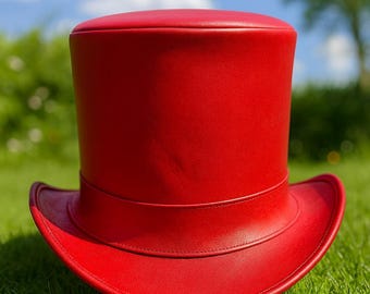 May include: A vibrant red top hat with a cylindrical crown and a wide, curved brim. The hat is made of a smooth material and sits on a bed of green grass. The hat's design is classic and eye-catching.