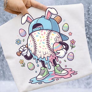 以下が含まれることがあります： ウサギの耳、水色の野球帽、溶けたアイスクリームのデザインが特徴の野球キャラクターが描かれた白いグラフィックTシャツ。野球はバットとイースターエッグを持っており、カラフルなスプリンクルとパステルカラーが特徴です。