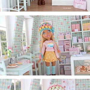 K&ouml;nnte beinhalten: Eine Puppe in einer Miniatur-B&auml;ckerei-Szene. Die Puppe tr&auml;gt ein rosa Oberteil, einen gelben Rock und einen bunten Hut. Die Szene umfasst eine Vitrine mit Geb&auml;ck, Regale mit Schachteln sowie einen kleinen Tisch und St&uuml;hle.