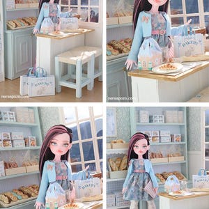 May include: A doll with long dark hair featuring pink highlights, wearing a light blue cardigan over a floral dress, white patterned tights, and pink boots. The doll stands in a miniature bakery setting with shelves of bread and a small table.