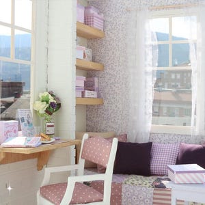 Pode incluir: Uma cena de quarto em miniatura com uma janela, secret&aacute;ria e &aacute;rea de estar. O quarto apresenta um esquema de cores branco e rosa, com papel de parede floral, prateleiras e caixas decorativas. Uma pequena mesa cont&eacute;m um livro e uma caixa de presente.